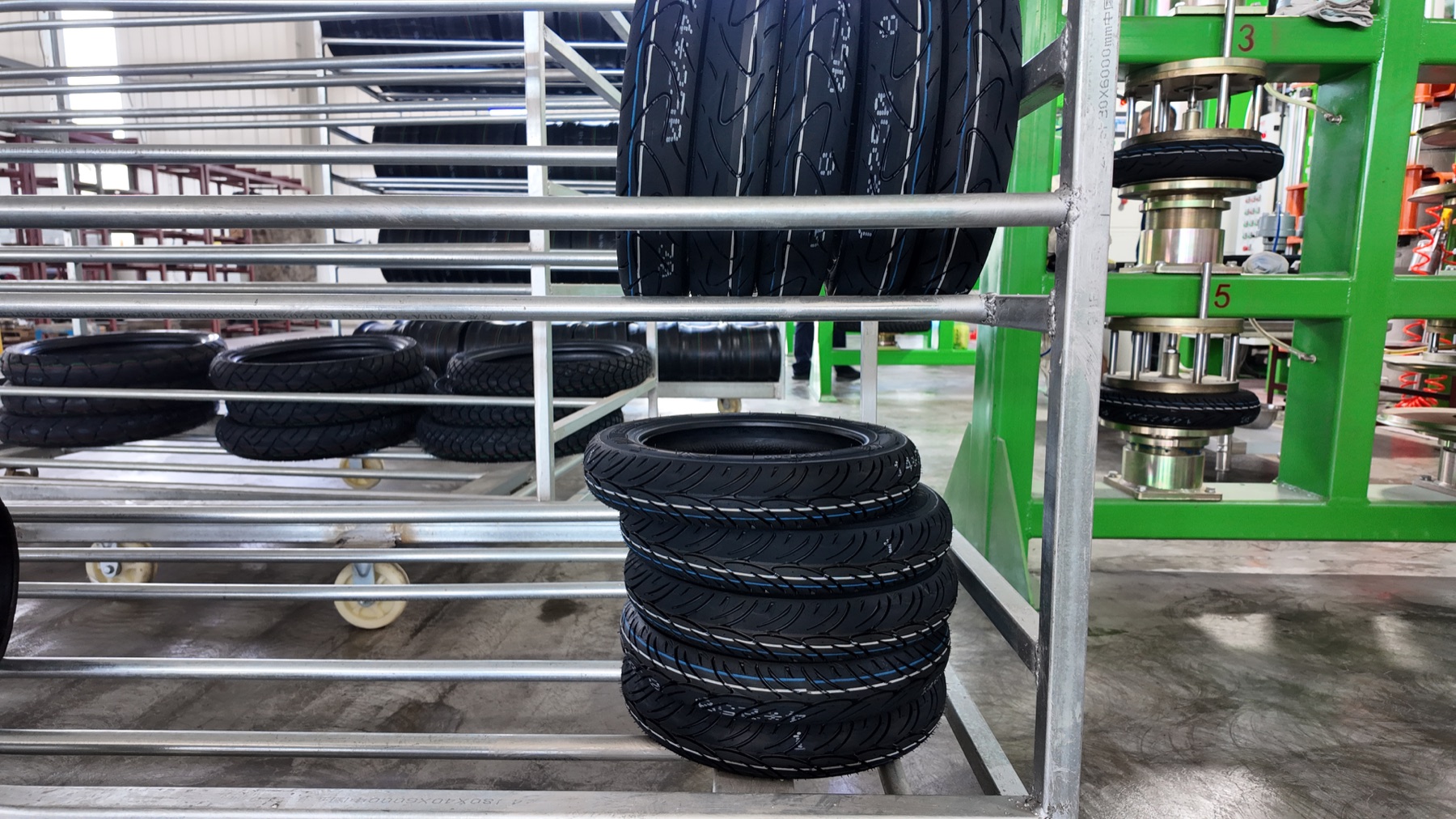 Finished motorcycle tyres photographed beside production equipment